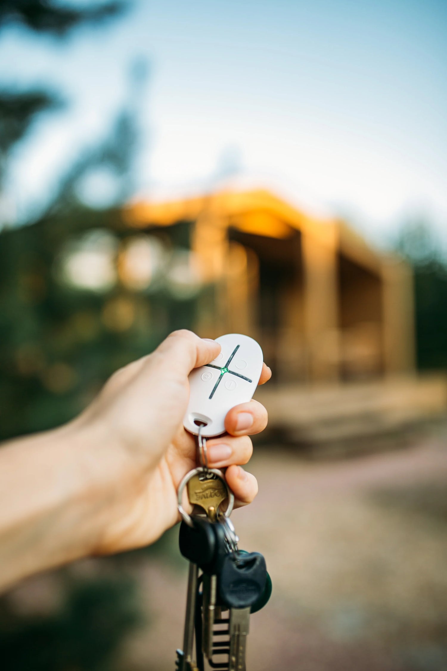 Una mano tiene un telecomando Ajax System collegata alle chiavi di casa